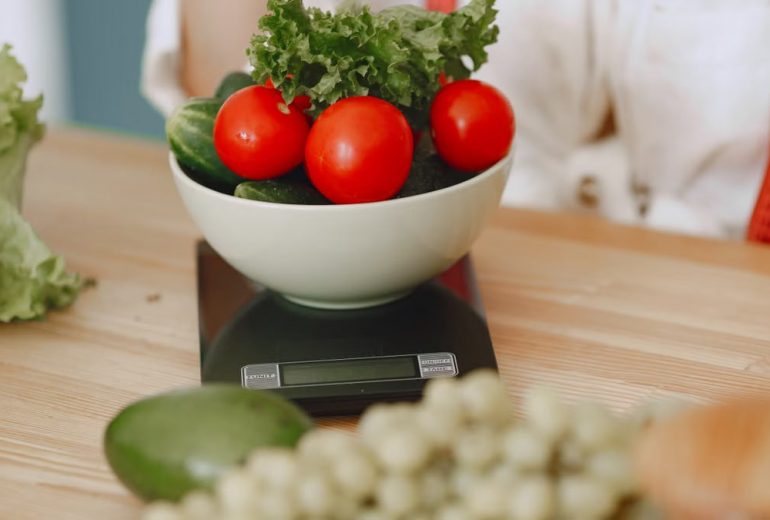 Colorful fresh vegetables including tomatoes and cucumbers on a kitchen scale for healthy eating.