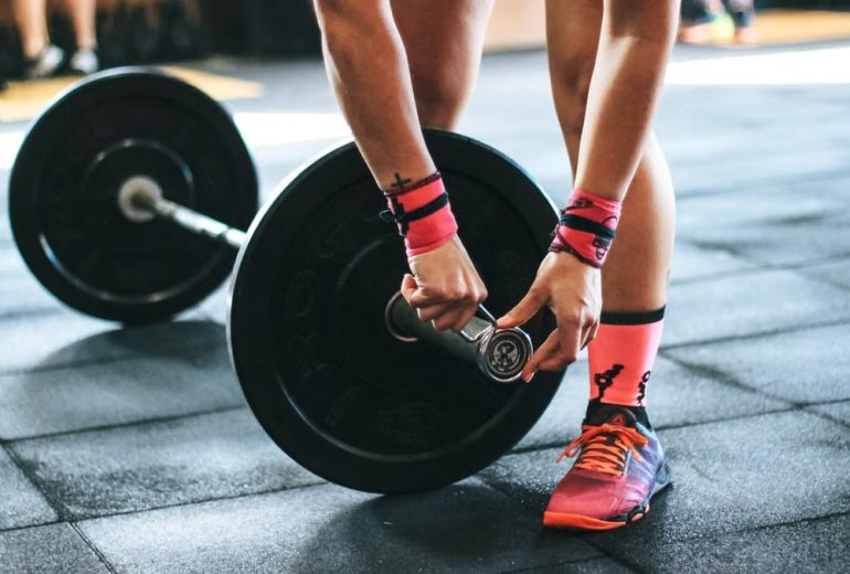 Athlete tightening barbell plates in a gym, emphasizing fitness and strength.
