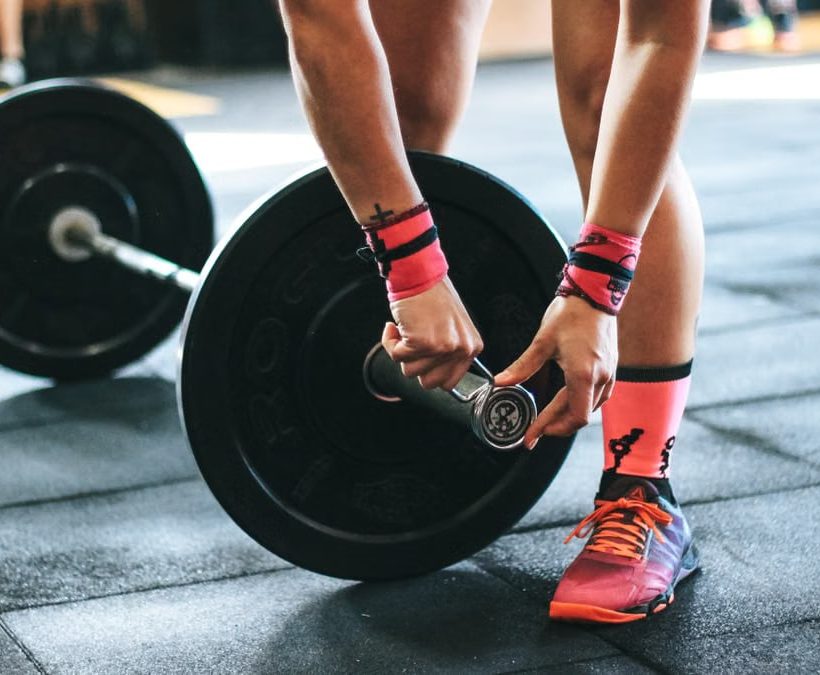 Athlete tightening barbell plates in a gym, emphasizing fitness and strength.