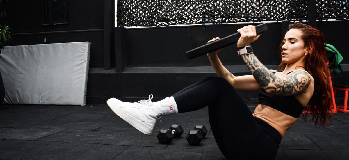 A determined woman performs a core workout in an indoor gym setting.